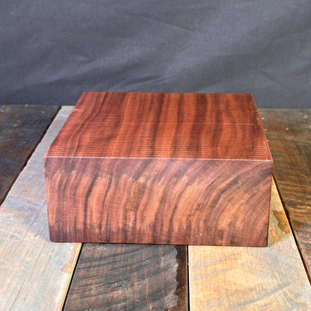 Close-up of a wooden block with a dark brown finish on a gray background
