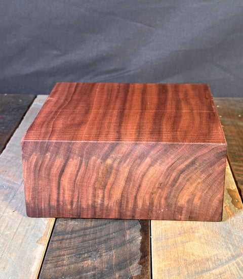 Close-up of a wooden block with a dark brown finish on a gray background